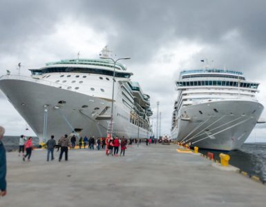 Image of A Large Two White Cruise Ships Landing In The Shipyard Infront of the tourists.