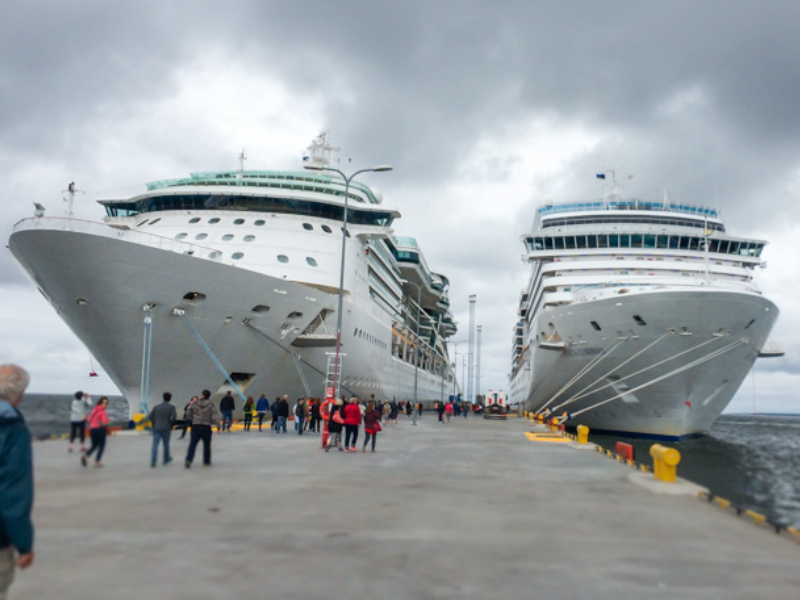Image of A Large Two White Cruise Ships Landing In The Shipyard Infront of the tourists.